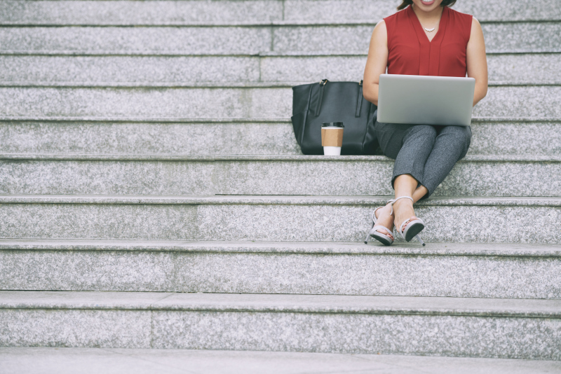 Woman sitting on outdoor steps using a laptop, symbolizing financial independence and modern work lifestyle. Source: https://www.freepik.com/free-photo/business-lady-resting-stairs_5576695.htm 