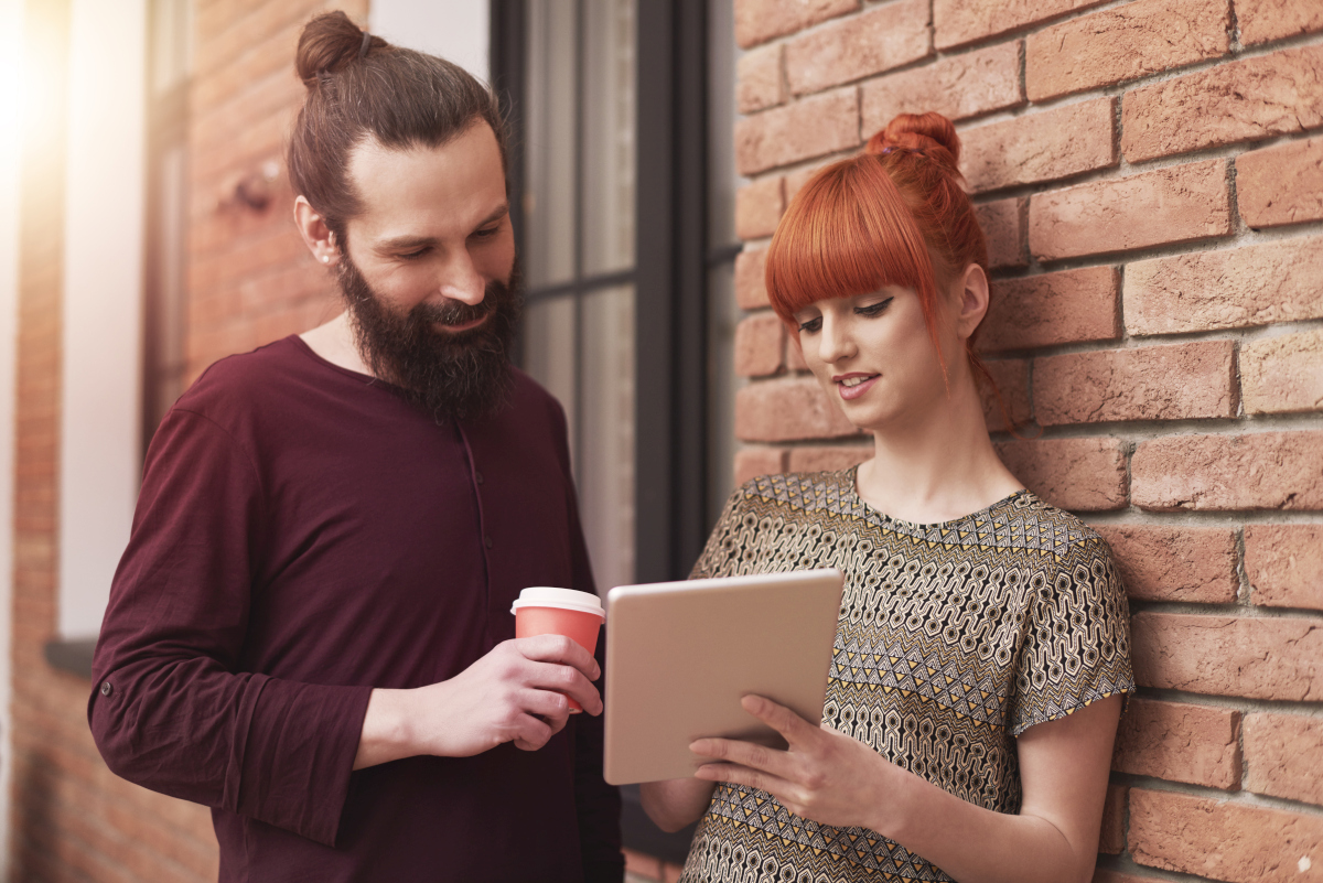 Two colleagues standing outdoors with coffee and a tablet while discussing content from a newsletter or marketing email. Source: https://www.magnific.com/free-photo/group-creative-people-analyzing-result-work_13250322.htm