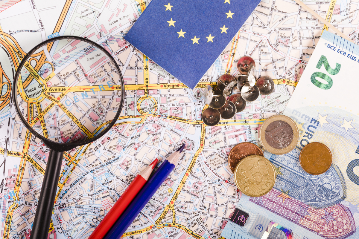 Magnifying glass on a European map with euro coins and banknotes, representing business and investment opportunities in Europe. Image created with AI