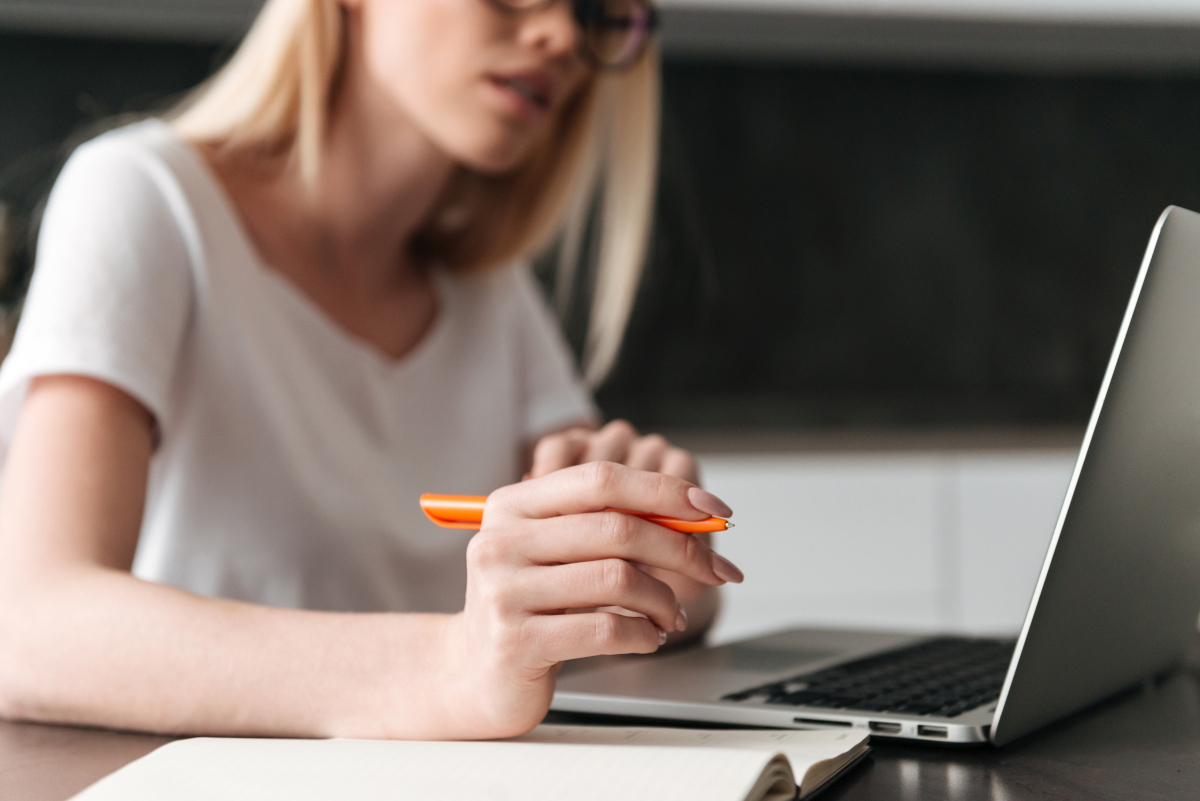 Woman planning and writing a marketing email while working on a laptop with a notebook beside her. Source: https://www.magnific.com/free-photo/cropped-photo-young-businesswoman-working-with-laptop-home_6819588.htm