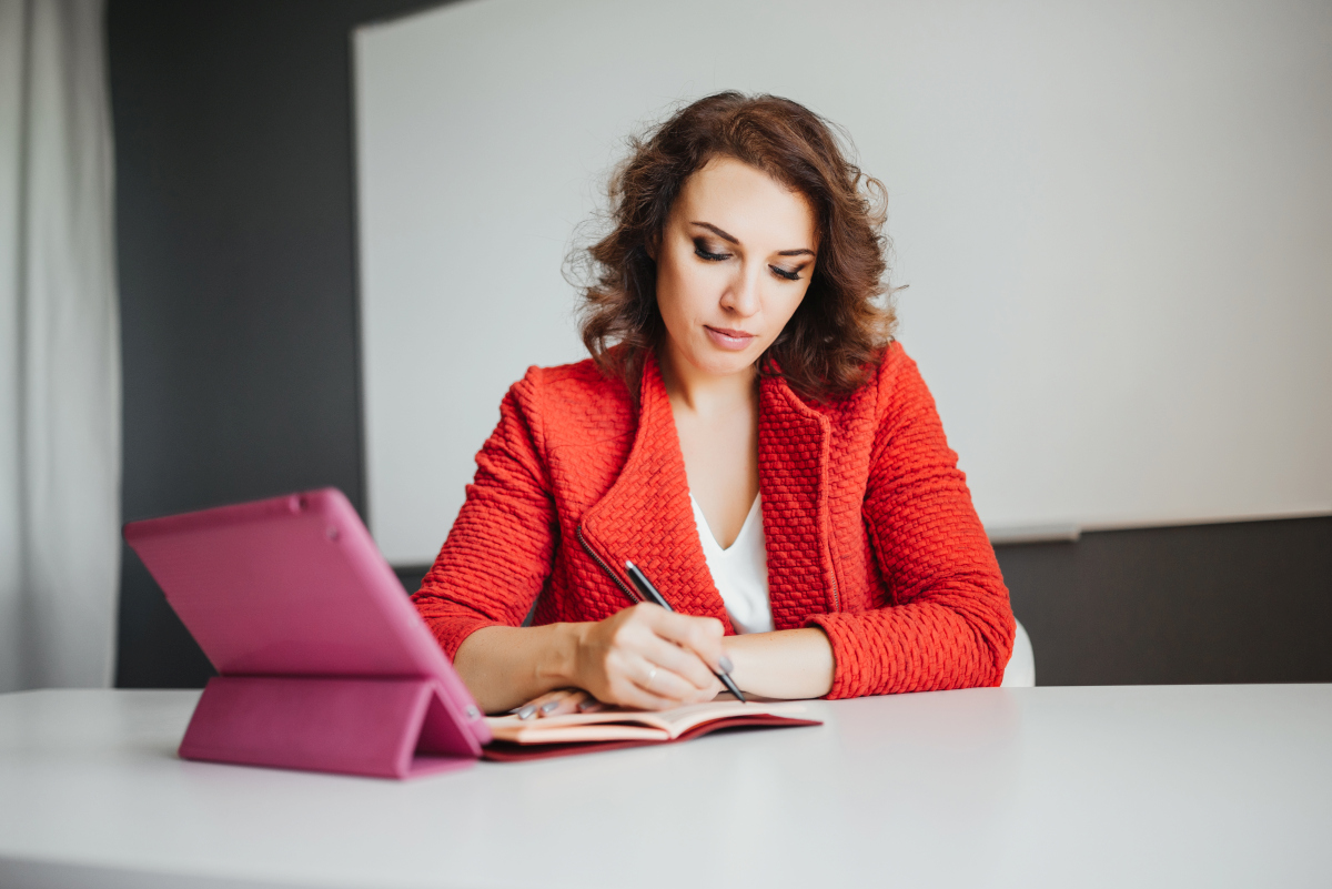 Businesswoman writing ideas in a notebook while working on a strategic plan. Source: https://www.magnific.com/free-photo/businesswoman-office-working-with-digital-tablet-other-documents_2455581.htm