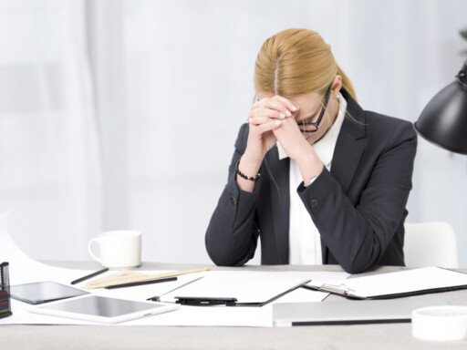 A frustrated businesswoman sitting at her desk with paperwork, a tablet, and a laptop. Source: https://www.magnific.com/free-photo/frustrated-young-businesswoman-workplace-with-paper-digital-tablet-laptop-desk_4048021.htm