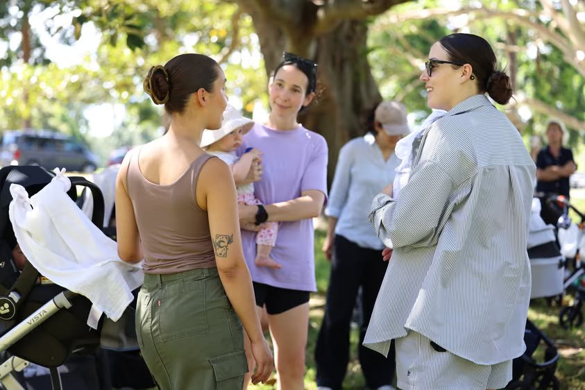 Mothers chat with their babies and prams at a Villagehood picnic in a park.Photo credit: Photo courtesy of Brittany Bloomer / Villagehood.